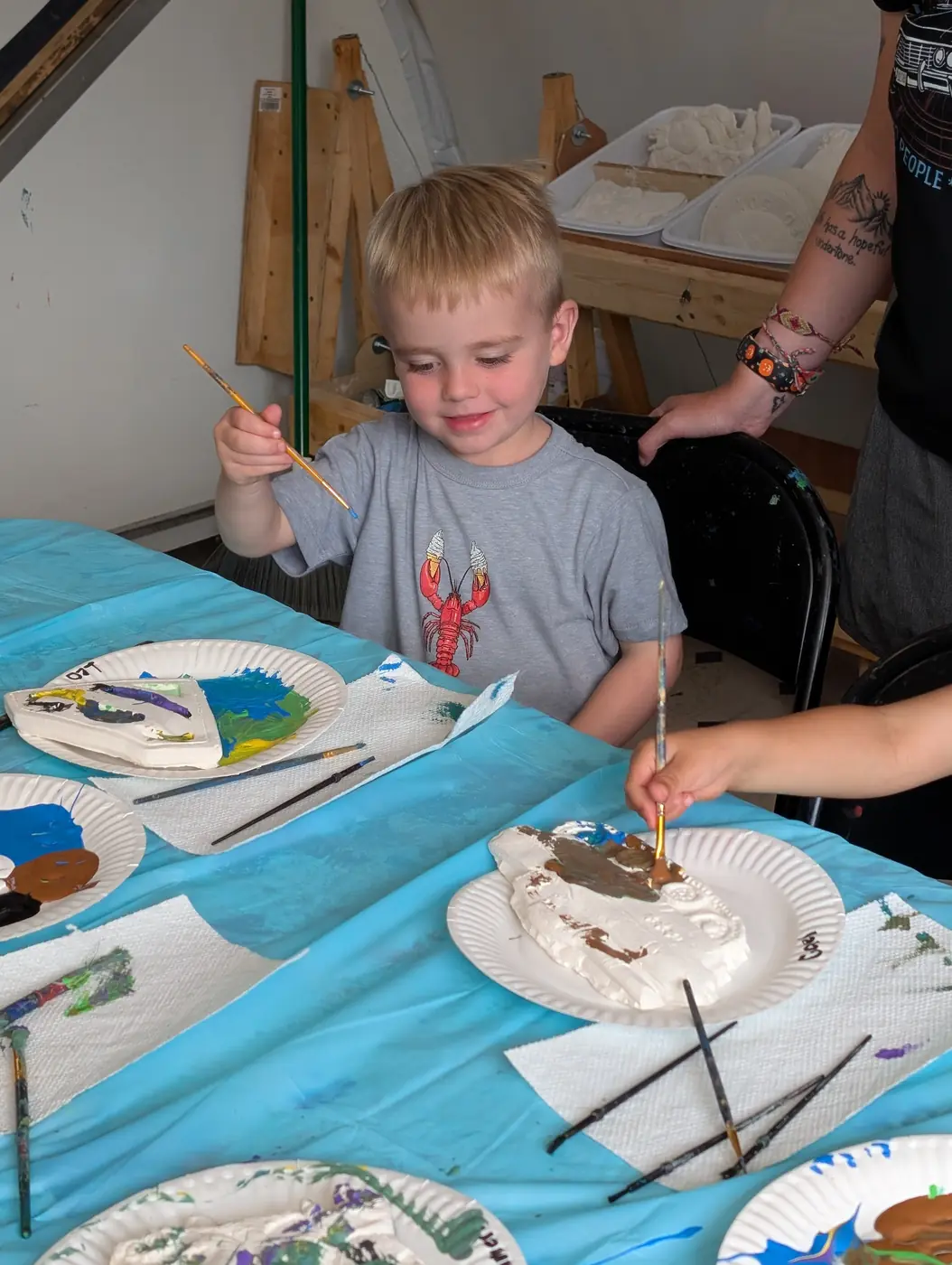 A child painting a handmade clay sea creature at Blossom Station's summer art studio