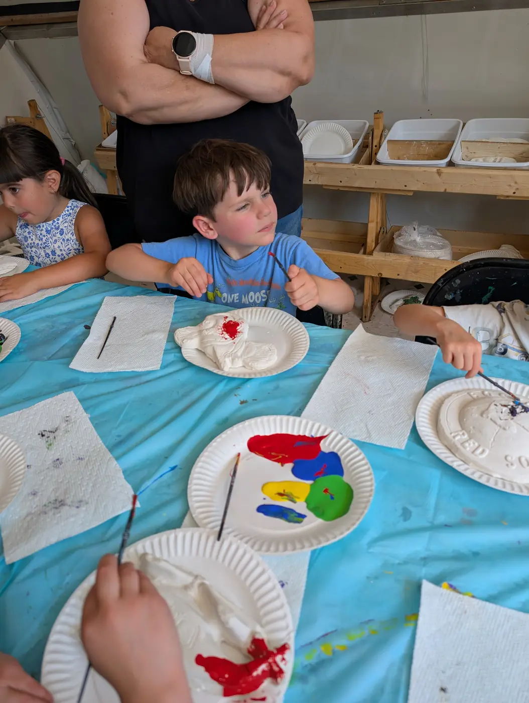 Children painting handmade clay plates together at Blossom Station's summer art studio