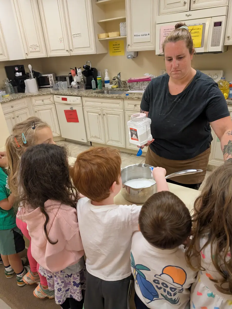 Children gathered around a teacher to make playdough together at Blossom Station