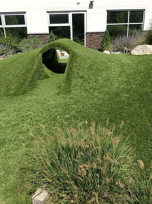 The grass tunnel and natural play mounds on the Blossom Station playground in Acton, MA