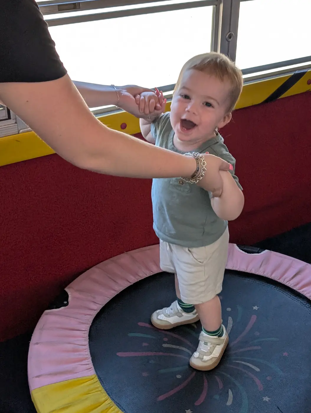 A joyful toddler bouncing on the play-bus trampoline at Blossom Station's summer program
