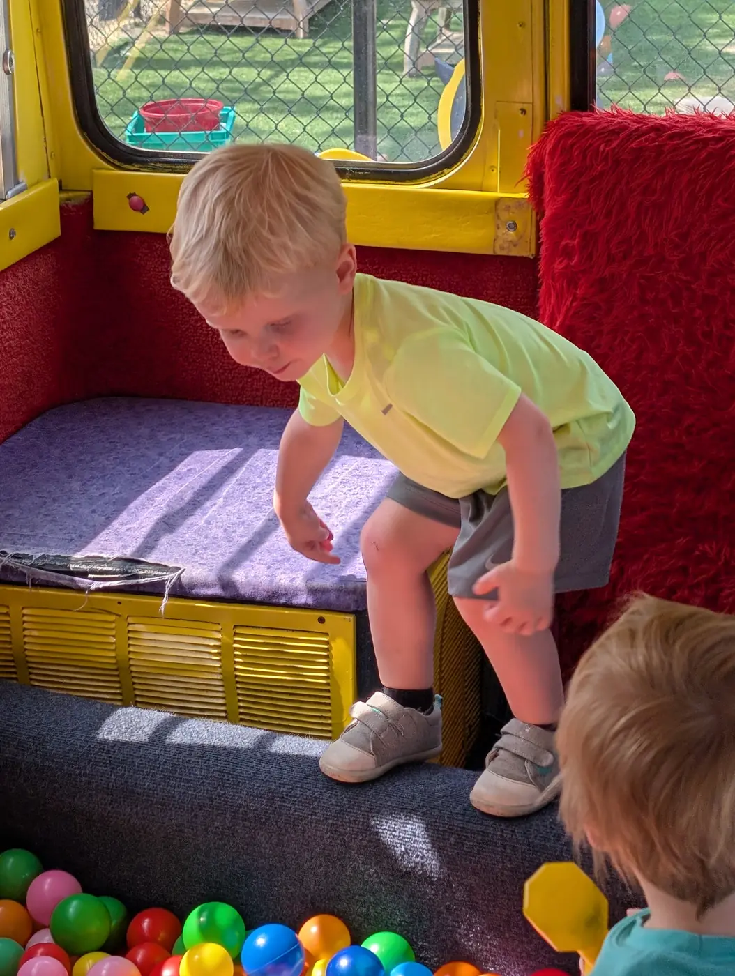A child exploring the play-bus ball pit at Blossom Station