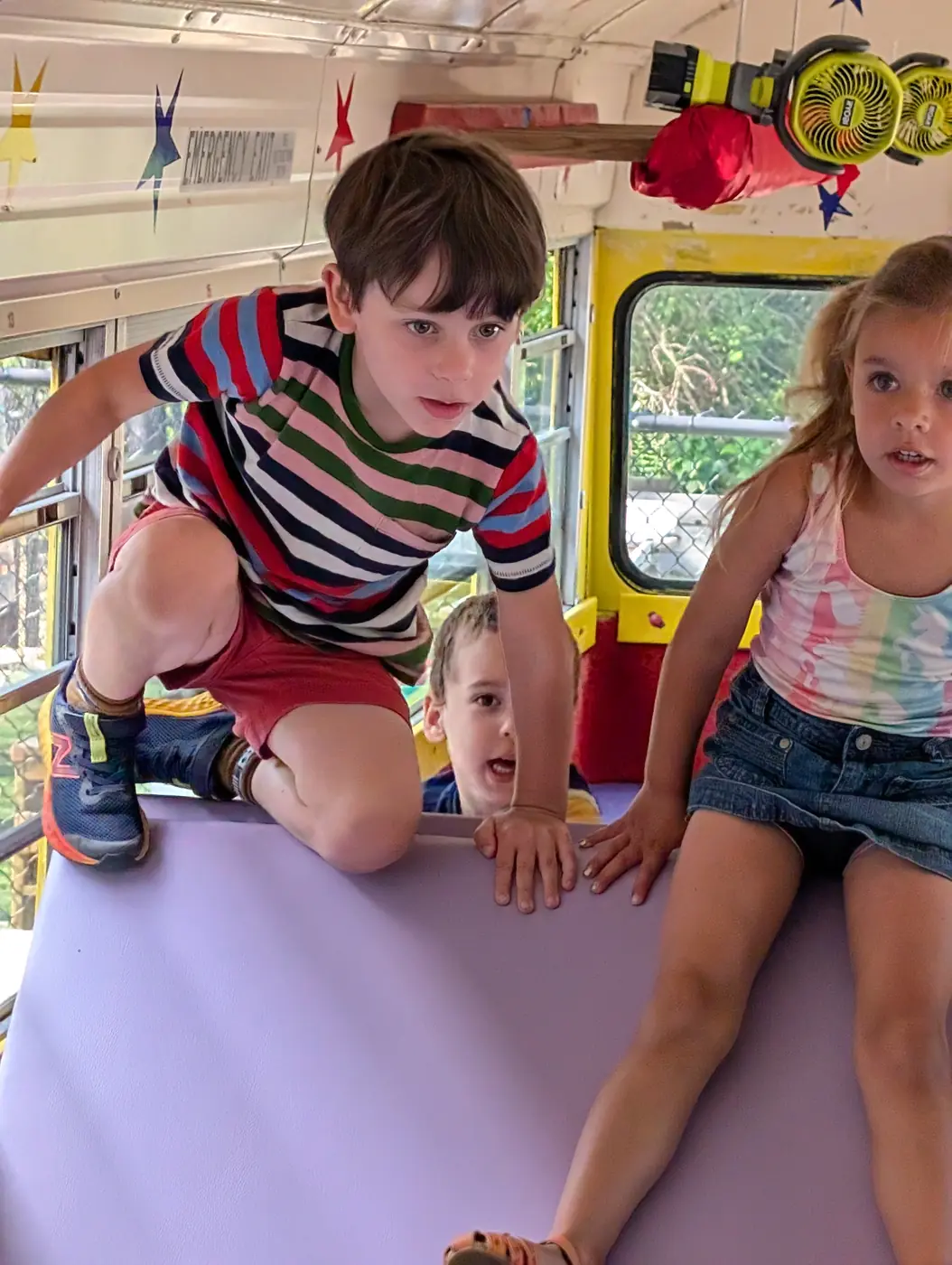 Children climbing in the play bus during Blossom Station's summer program