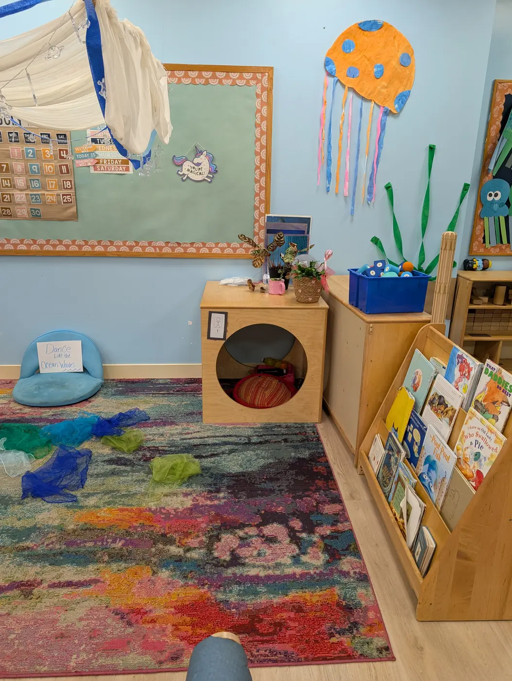 A cozy reading nook with books and a colorful rug at Blossom Station in Acton, MA