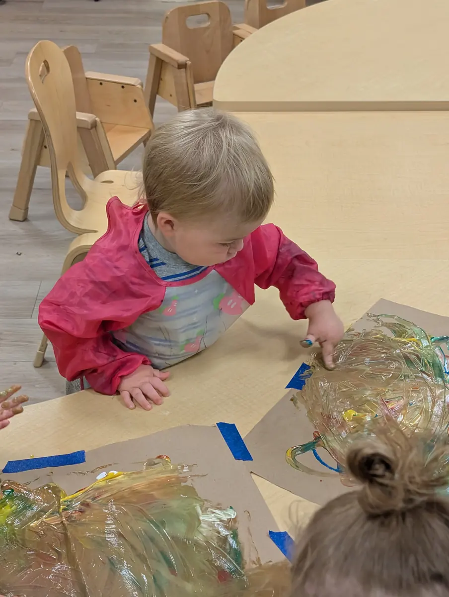 A child exploring colorful sensory gel paint during a messy art activity at Blossom Station