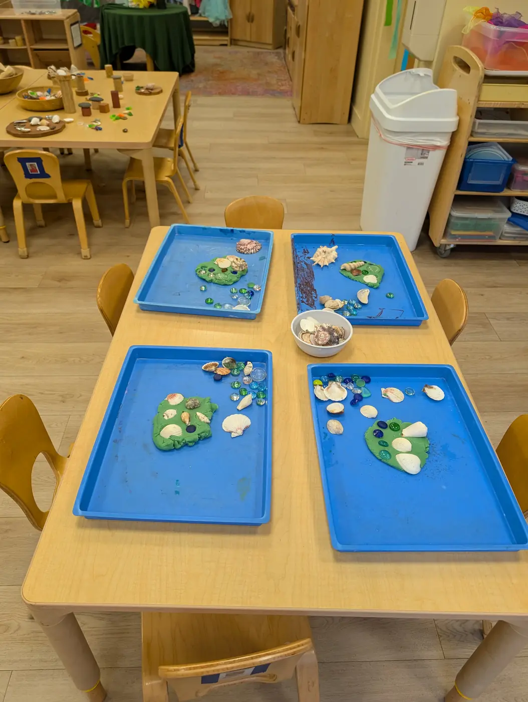 A sensory tray with playdough and seashells from the summer ocean theme at Blossom Station