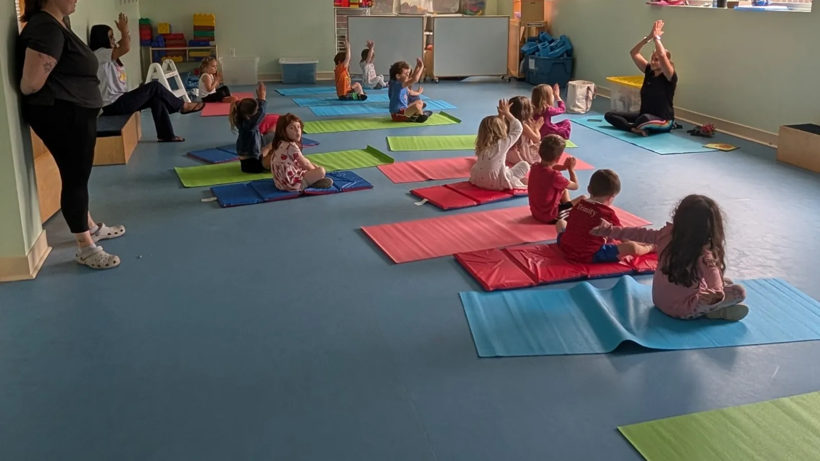 Preschoolers on colorful yoga mats raising their arms with their instructor at Blossom Station in Acton, MA